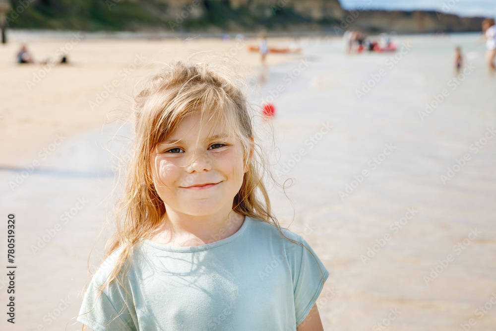 Happy preschool girl having fun on the sand beach Omaha at Atlantic coast of Normandy, France. Outdoor summer activities for kids Happy preschool girl having fun on the sand beach Omaha at Atlantic coast of Normandy, France. Outdoor summer activities for kids