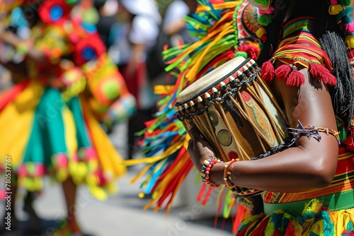 A person is holding a drum in a parade. The drum is colorful and has a lot of strings. The parade is lively and full of energy