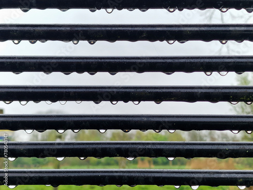 Abstract pattern of raindrops on bars of steel park bench