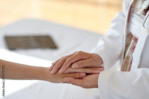 Closeup image of doctor touching hands of sick teenage girl to reassure her