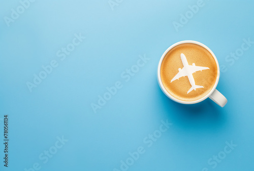Draufsicht, Weiße Tasse mit Kaffe und Flugzeug Latte Art im Milchschaum isoliert auf blauem Hintergrund - Konzept für entspanntes Reisen, Reiselust