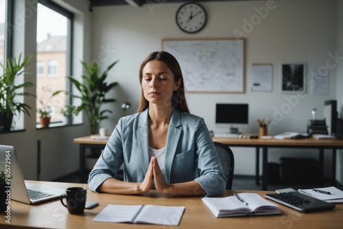 Woman meditating at her desk in office photo