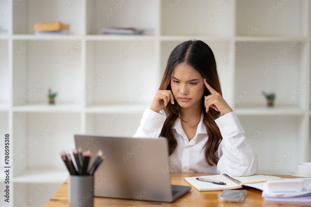 Businesswoman feeling stressed while working at her office desk with laptop, paperwork, and coffee cup. Businesswoman feeling stressed while working at her office desk with laptop, paperwork, and coffee cup.