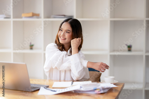 A relaxed businesswoman stretch and relieve tension while working at her desk in a bright office.