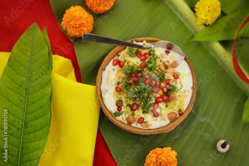 Indian Chaat Dahi Bhalle with Curd and Sweet Sauce on banana leaf with indian backdrop