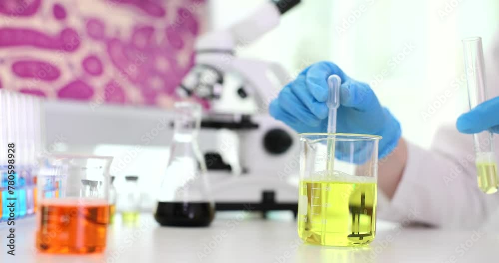 Chemist pouring yellow liquid from flask into test tube in laboratory closeup 4k movie slow motion. Chemical and biological experiments concept Chemist pouring yellow liquid from flask into test tube in laboratory closeup 4k movie slow motion. Chemical and biological experiments concept