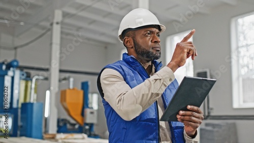 Close-up of tall good-looking bearded African-American male measuring comparing and looking in his gadget. Serious worker moving his head counting and distributing updated information. photo