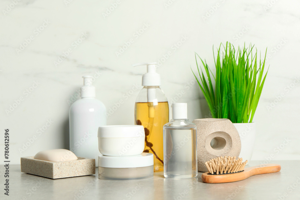 Brush and personal care products on gray table near white marble wall