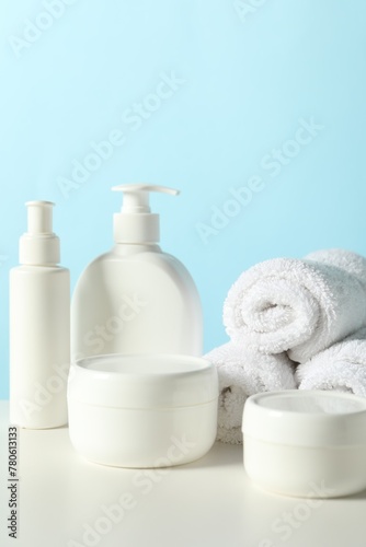 Different bath accessories on white table against light blue background