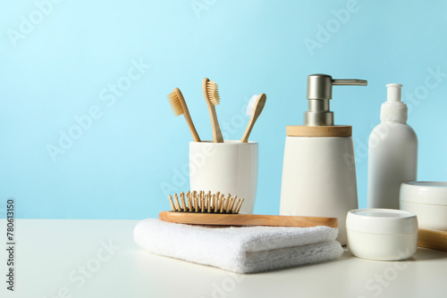 Different bath accessories on white table against light blue background. Space for text