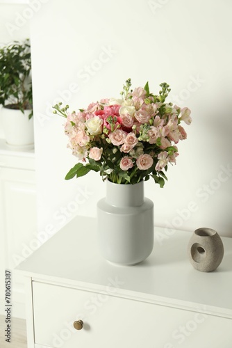 Beautiful bouquet of fresh flowers in vase on chest of drawers indoors