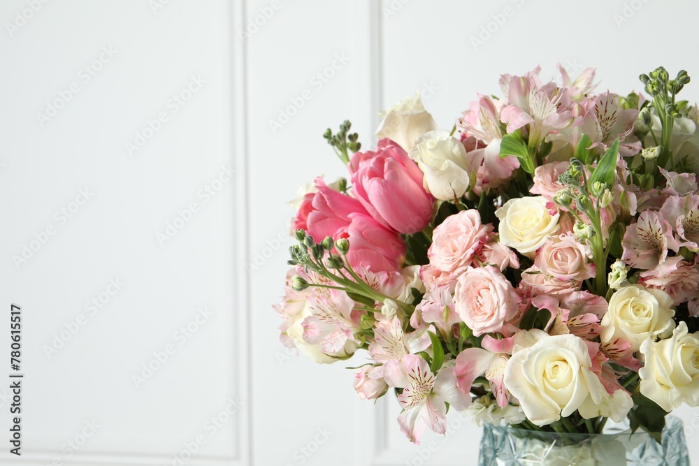 Beautiful bouquet of fresh flowers in vase near white wall. Space for text
