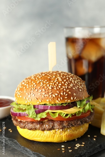 Burger with delicious patty, soda drink, french fries and sauce on table against gray background, closeup