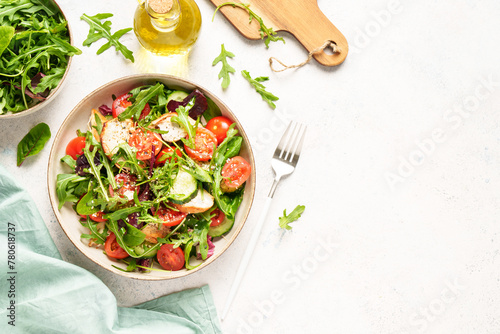 Green salad with baked chicken breast, fresh salad leaves and vegetables. Top view on white background. © nadianb