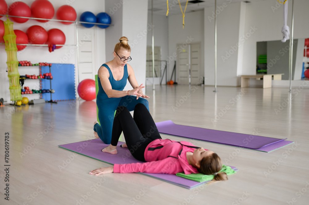 PePersonal fitness trainer trains woman in Pilates club, correcting her posture and telling her how to do exercises correctly. Concept of fitness, rehabilitation, pain treatment, stretching