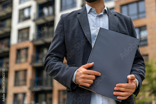 Handsome real estate agent holds a folder in hands.