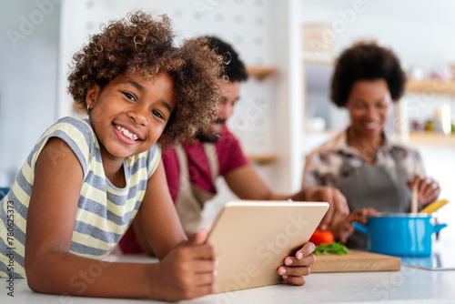 Happy african family having fun with device at home. Black parents and child using digital tablet