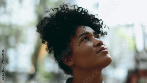Thoughtful Young African Descent Brazilian Female Looking Skyward in Hope, Pensive Close-Up Face of 20s Woman in Meditation photo