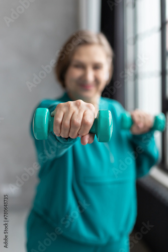 Happy active mature woman with dumbbells in a gym. Sport lifestyle