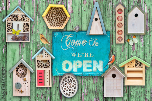 Birdhouses and insect hotels with birds and insects with welcome come in sign
