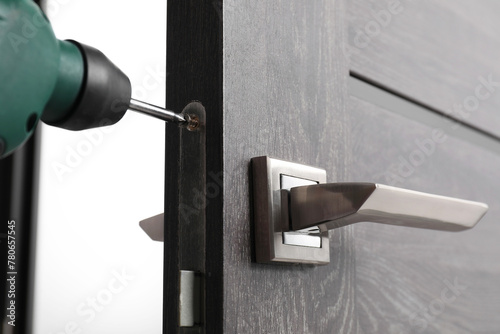 Repairing door handle with electric screwdriver indoors, closeup © New Africa