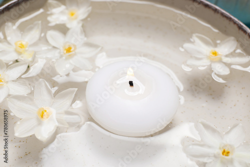 Spa composition with burning candle and beautiful flowers in water  closeup