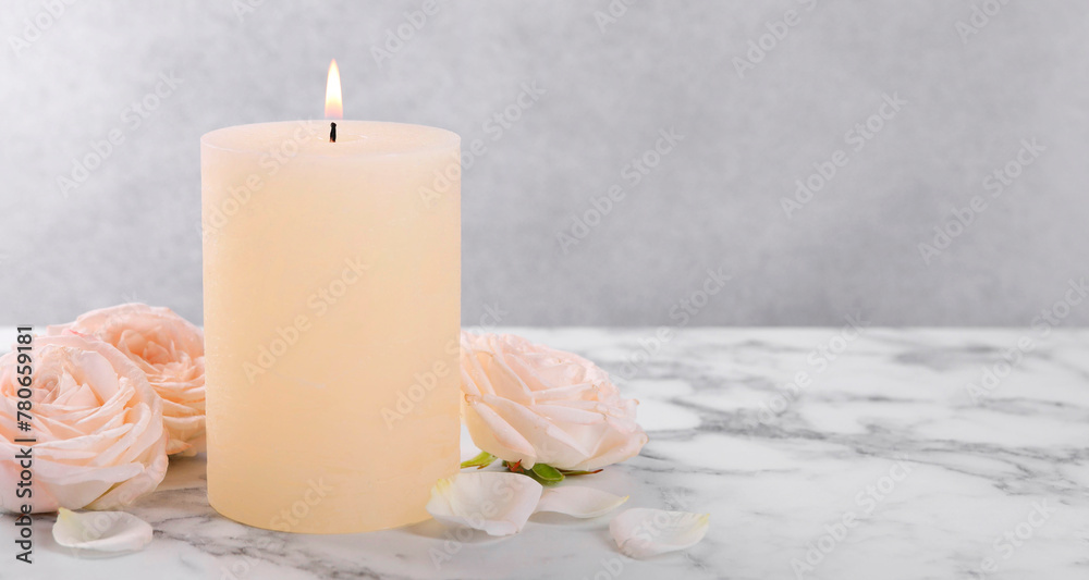 Spa composition with burning candle and flowers on white marble table, space for text