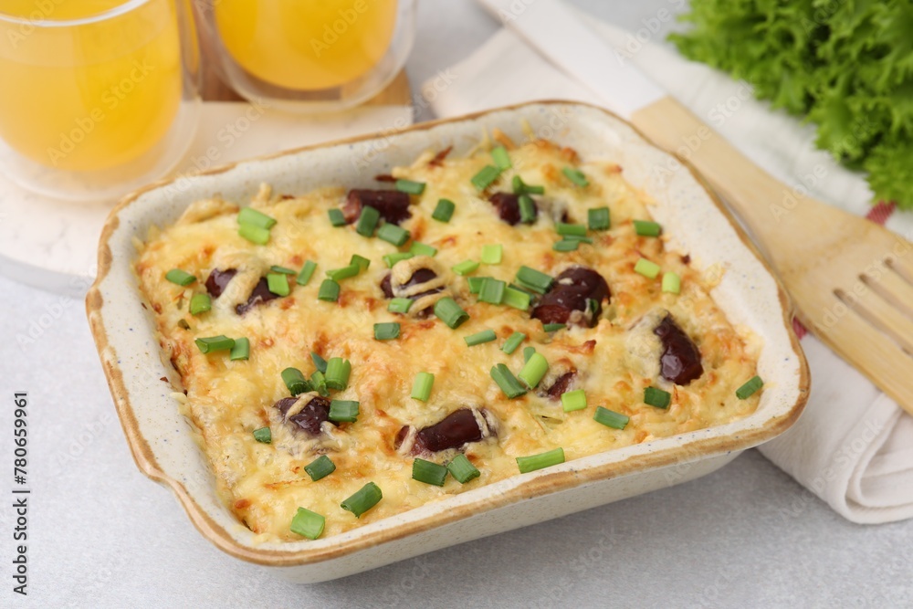 Tasty sausage casserole with green onions in baking dish on white table, closeup Tasty sausage casserole with green onions in baking dish on white table, closeup