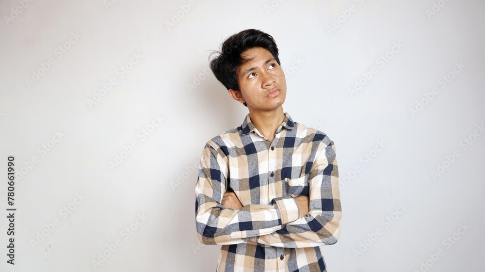 Young Asian man thinking while looking up with crossed arms Young Asian man thinking while looking up with crossed arms