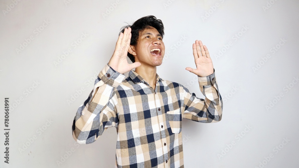 Angry young Asian man raising hands and shouting with aggressive expression Angry young Asian man raising hands and shouting with aggressive expression