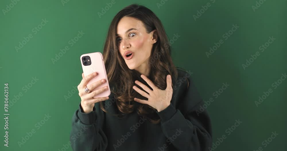 Attractive brunette woman look surprised wow hold using mobile cell phone on green background. Girl look on smartphone and doing winner gesture. Girl just found out big win news, wow. Attractive brunette woman look surprised wow hold using mobile cell phone on green background. Girl look on smartphone and doing winner gesture. Girl just found out big win news, wow.