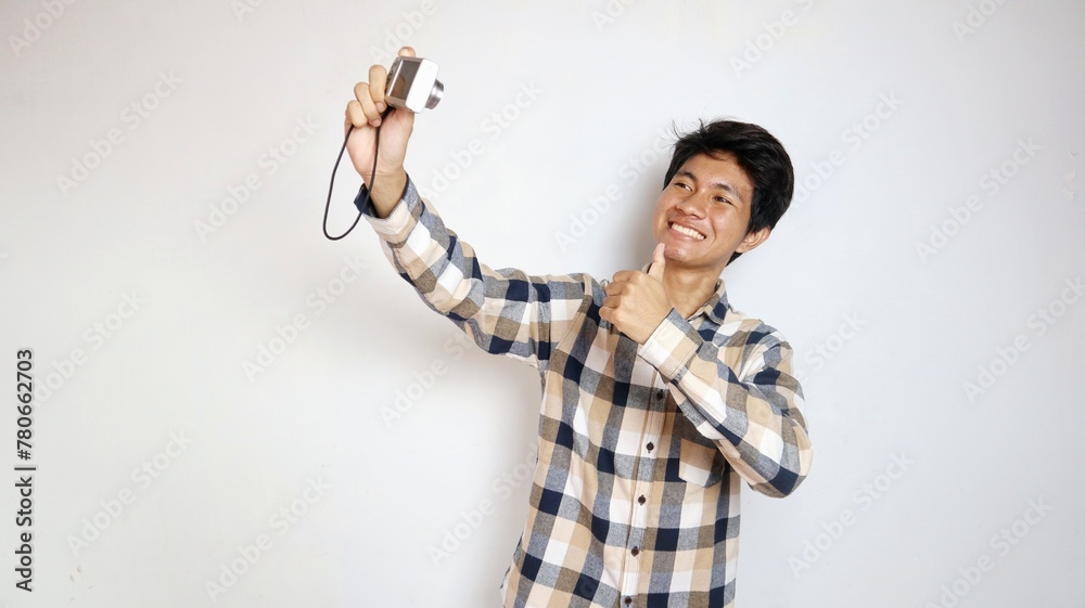 Handsome young Asian man happily taking photos using pocket camera Handsome young Asian man happily taking photos using pocket camera