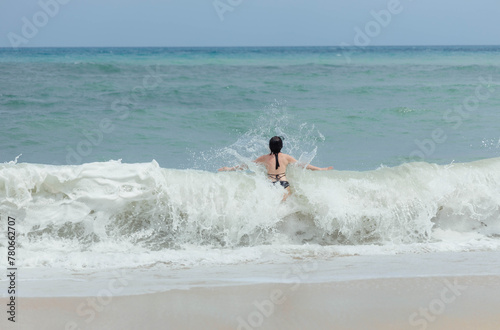 Woman splashes through the frothy waves at the beach