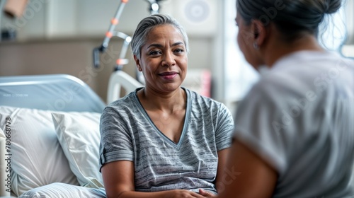 Elderly African woman in hospital bed having a conversation with healthcare professional photo