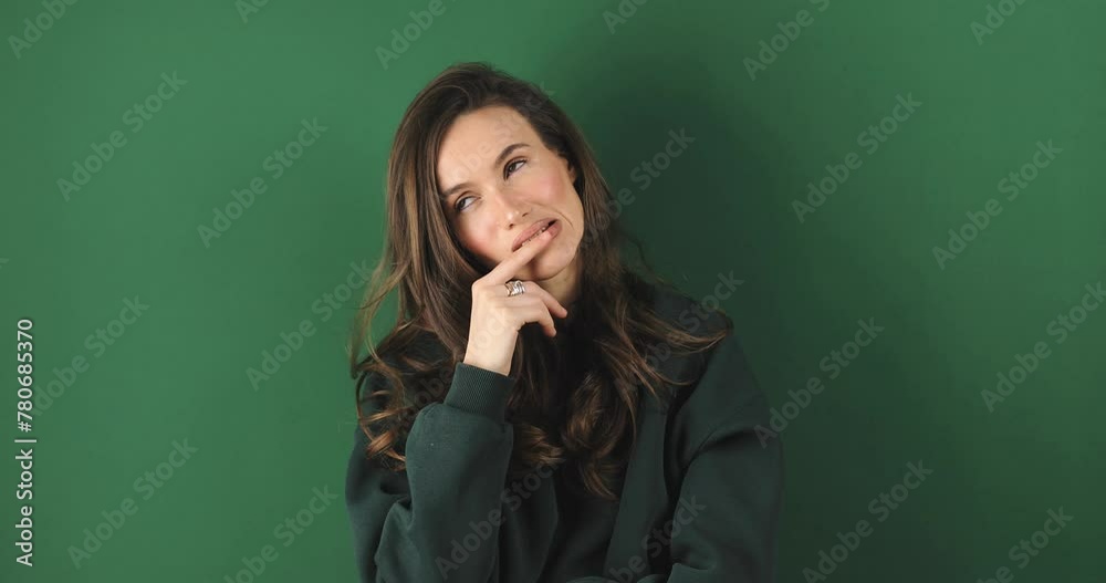 Need to think! Pensive doubting woman in green sweatshirt imagining in mind, wondering difficult solution, touch lips, feeling confused, not sure about choice. Studio shot isolated on green background Need to think! Pensive doubting woman in green sweatshirt imagining in mind, wondering difficult solution, touch lips, feeling confused, not sure about choice. Studio shot isolated on green background