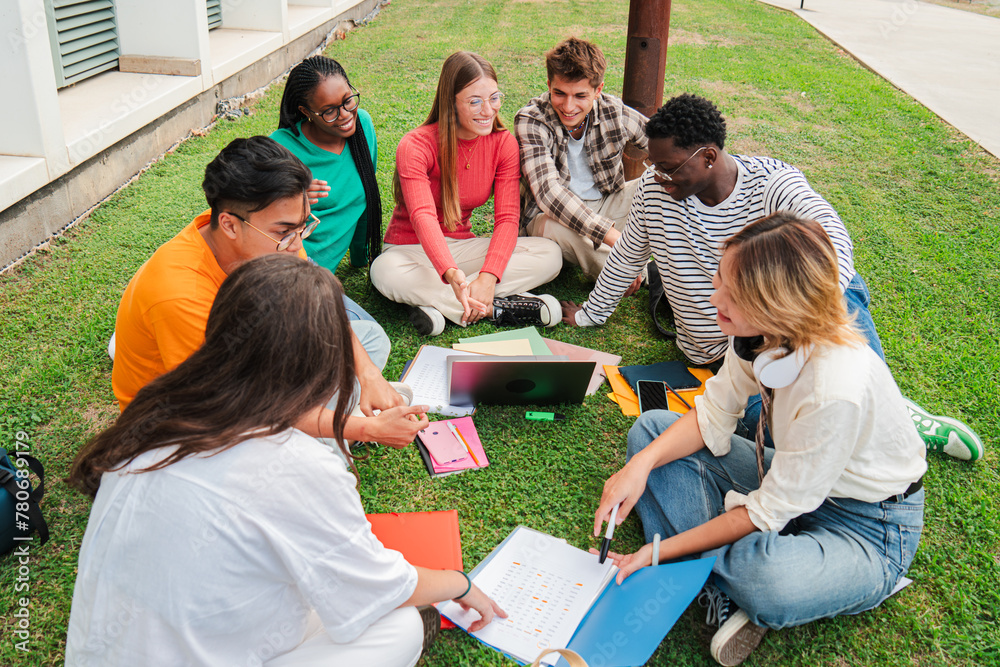 Multiracial students using a laptop computert sitting in a circle on ...
