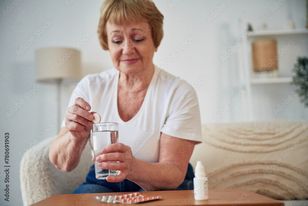 Self medicate. Taking medicine. Senior elderly woman is at home in the living room Self medicate. Taking medicine. Senior elderly woman is at home in the living room