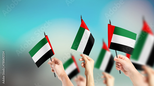 A group of people are holding small flags of United Arab Emirates in their hands. photo