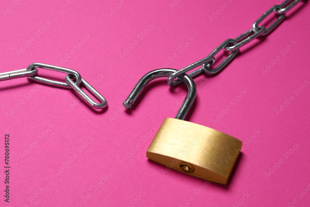 Steel padlock and chain on pink background, closeup Steel padlock and chain on pink background, closeup