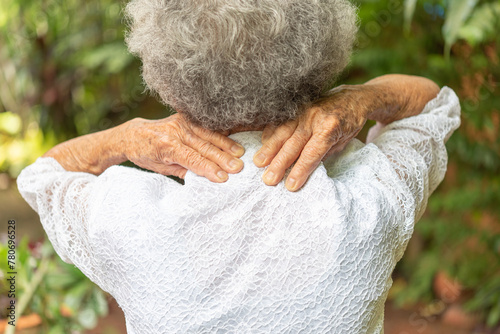 Senior woman has shoulder pain, back view, with copy space .