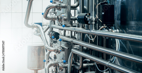 Stainless steel pipes and tanks, high-tech industrial fluid processing system. Many shiny metallic tubes, valves, and gauges. Pharmaceutical or food and beverage industries.