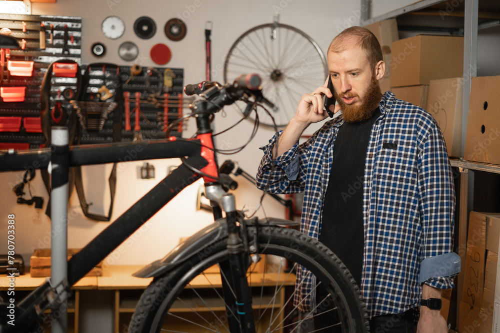 Portrait of handyman standing with phone in equipped workshop or garage. DIY