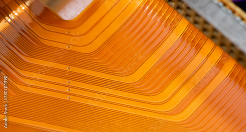 Fotografie A detailed close-up of a copper colored flexible flat ribbon cable with parallel