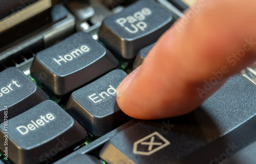 Man pressing the End key on a laptop computer keyboard, finger closeup, one person. Ending an activity, finishing work or a task, leaving, putting an end to something abstract concept, symbol