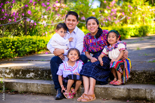 A happy and united family takes a portrait sitting in a park in their city.