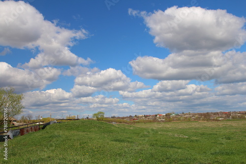 A grassy field with a fence and a blue sky with clouds © parpalac