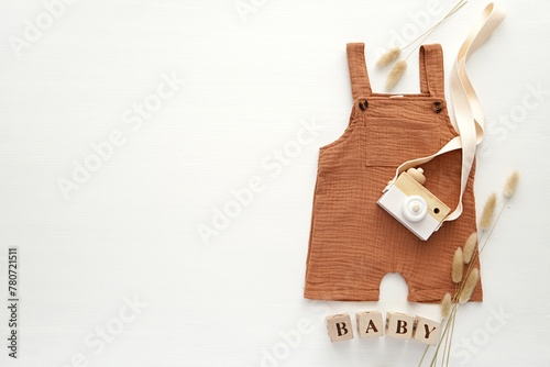 White wooden background with copy space, baby clothes and accessories, aesthetic flat lay, nursery, baby waiting concept.