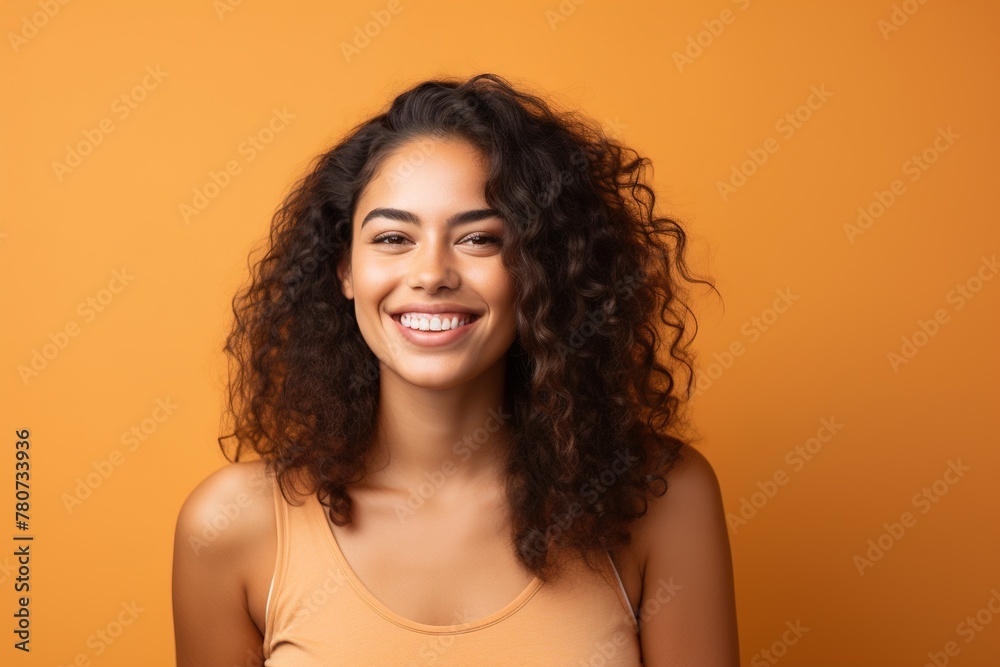 A woman with curly hair is smiling and wearing a yellow tank top A woman with curly hair is smiling and wearing a yellow tank top