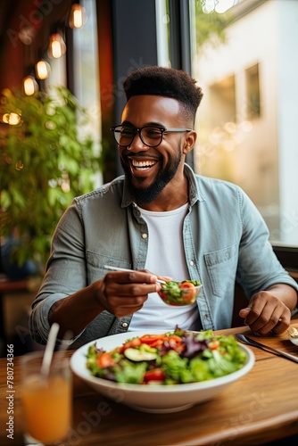 Man laughing while eating salad in cafe