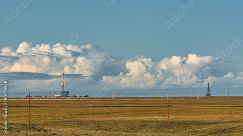 Landscape of the northern tundra in summer. On the horizon the infrastructure of drilling wells at an oil and gas field. Beautiful textured sky